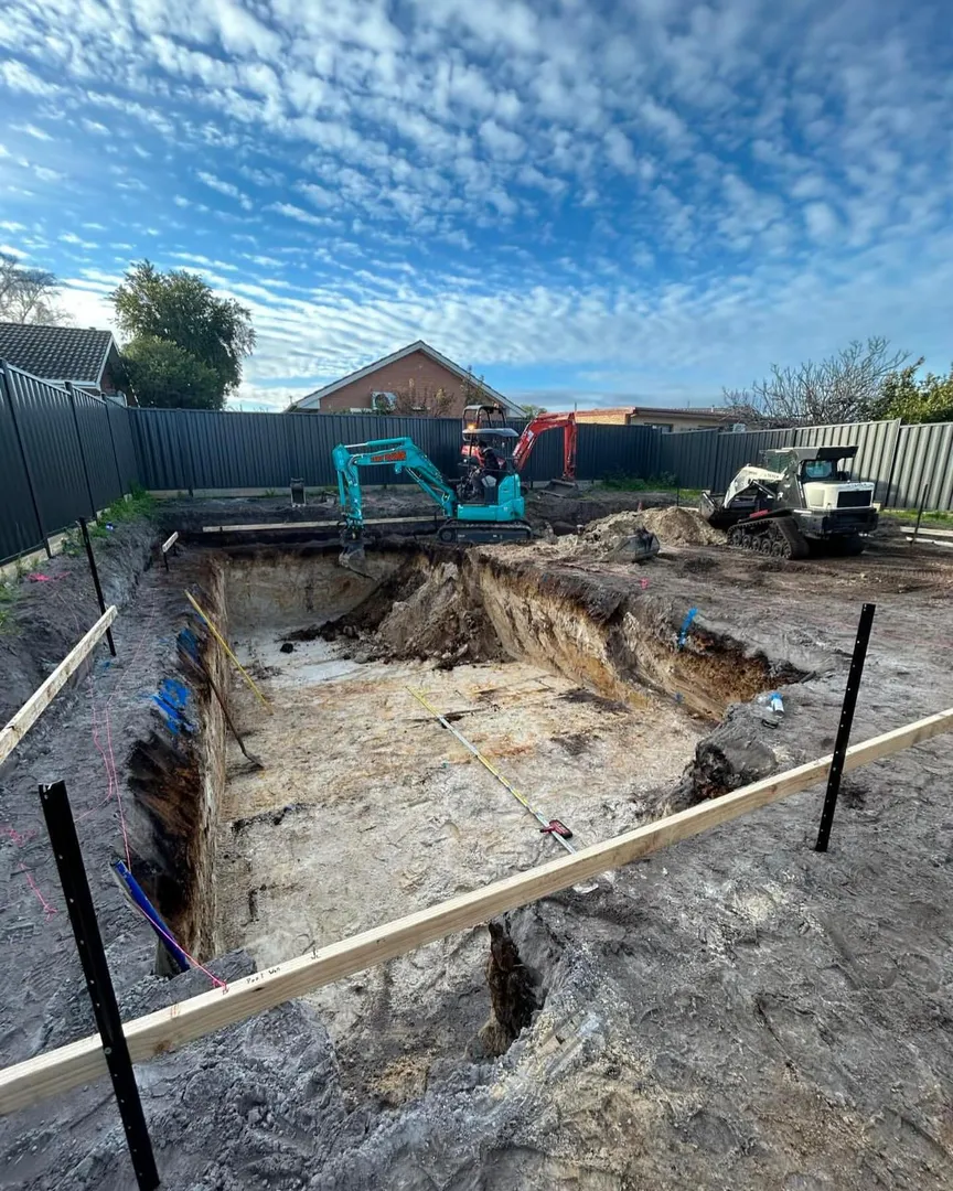 Excavator digging large hole at construction site.